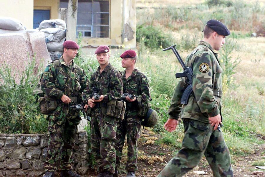 Солдат югославской армии проходит мимо солдат 1-й воздушно-десантной дивизии Великобритании по дороге к аэропорту Приштины 