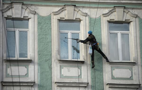 Промышленный альпинист моет окна здания на улице Воздвиженка в Москве