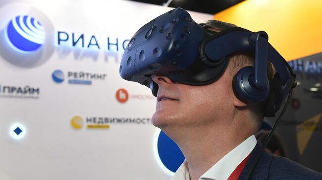 Руководитель Федерального агентства связи Олег Духовницкий VR очках виртуальной реальности на стенде МИА Россия сегодня во второй день ПМЭФ