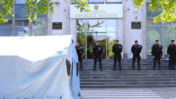 Сотрудники правоохранительных органов охраняют вход в здание правительства Молдавии во время митинга сторонников Демократической партии Молдавии