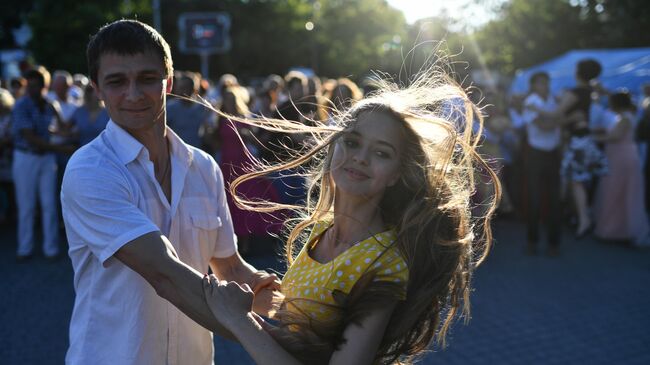 Молодые люди танцуют на общегородском балу на площади Нахимова в Севастополе