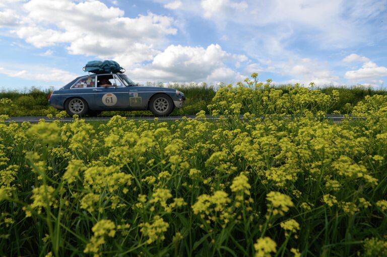 Участники международного ралли на старинных автомобилях Пекин - Париж 2019 на автомобиле MGB GT (1972 г.) на автомобильной дороге в Алтайском крае