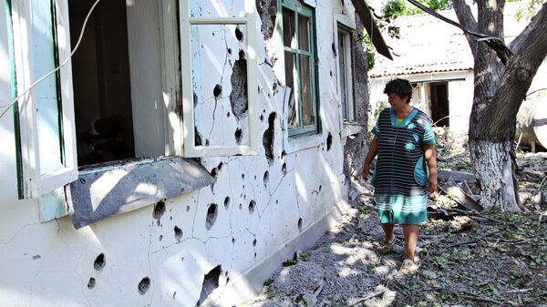 Женщина у жилого дома в поселке Новая Марьевка в Донецкой области, пострадавшего в результате ночного обстрела