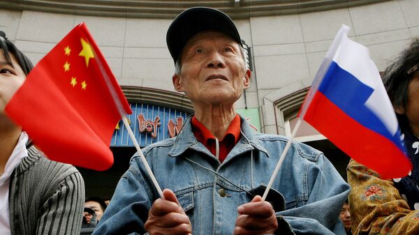 Пожилой мужчина держит китайский и российский флаги