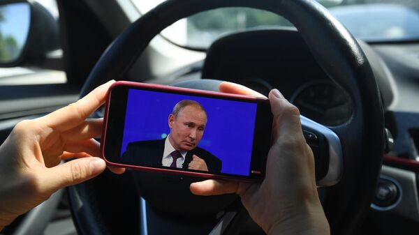 Девушка смотрит трансляцию прямой линии с президентом России Владимиром Путиным
