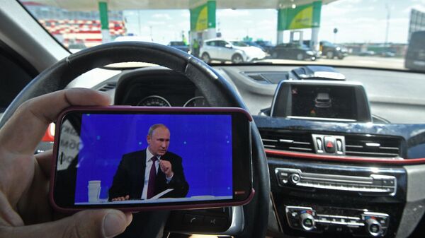 Мужчина смотрит трансляцию прямой линии с президентом России Владимиром Путиным