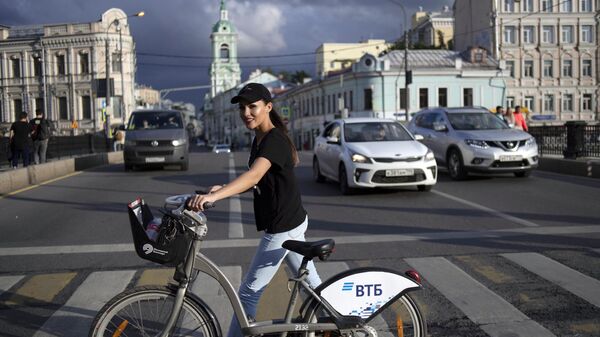 Девушка с велосипедом переходит Пятницкую улицу в Москве.