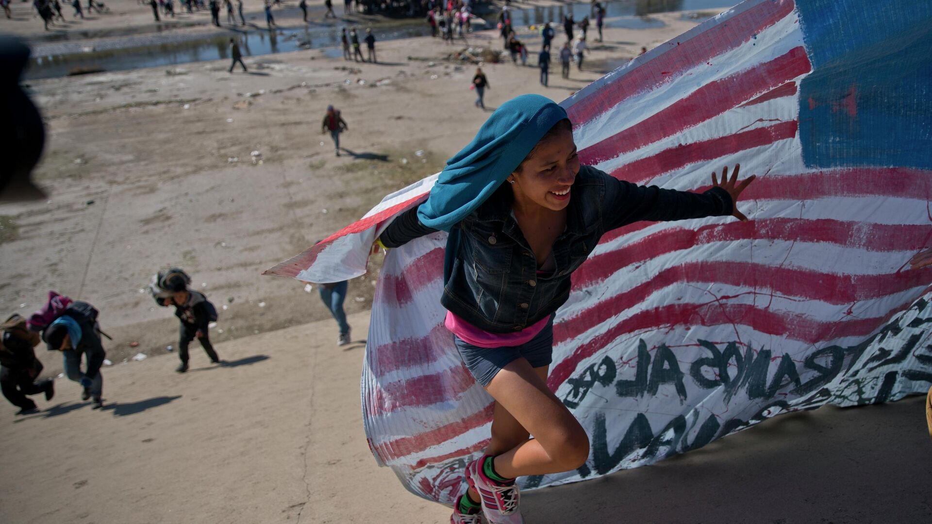 Мигрантка помогает нести американский флаг на границе Мексики и США - РИА Новости, 1920, 24.06.2022