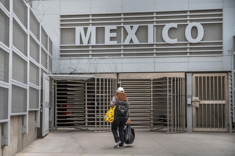 Женщина возвращается в Мексику из Сан-Исидро, штат Калифорния Женщина возвращается в Мексику из Сан-Исидро, штат Калифорния