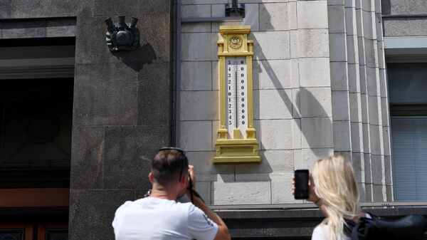 Молодые люди фотографируют термометр на здании Государственной Думы РФ в Москве