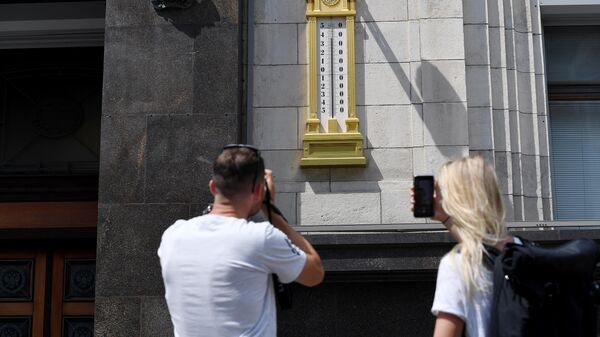 Молодые люди фотографируют термометр на здании Государственной Думы РФ в Москве