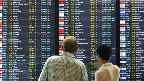 Пассажиры смотрят расписание авиарейсов в аэропорту 