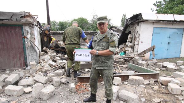Представители ДНР из Совместного центра по контролю и координации режима прекращения огня в Донбассе фиксируют разрушения от артиллерийских снарядов после обстрела. 25 июня 2019