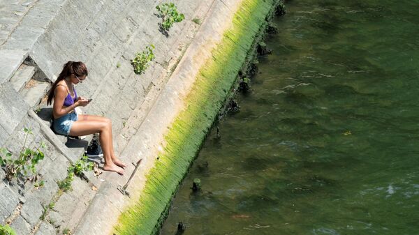 Женщина сидит на берегу реки Сены, Париж