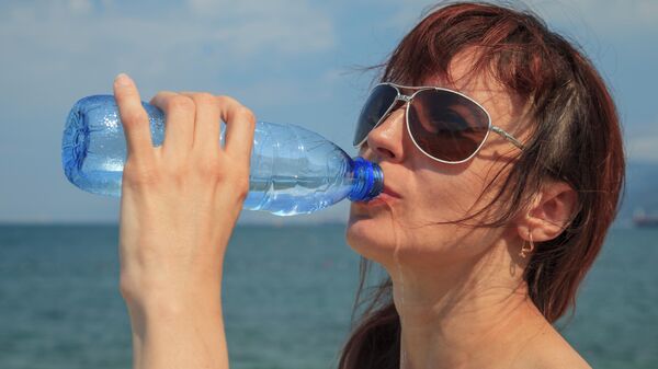 Девушка пьет из пластиковой бутылки
