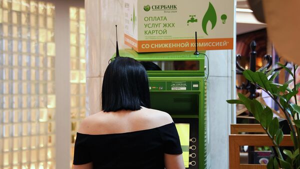 Девушка оплачивает коммунальные платежи в банкомате Сбербанка