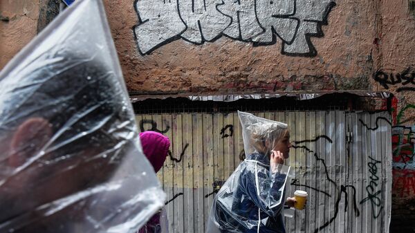 Молодые люди идут мимо граффити-тэга на фасаде дома в Дегтярном переулке