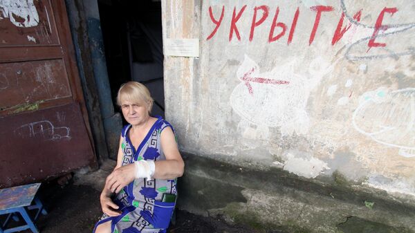Пенсионерка с раненой рукой сидит у входа в дом в Донецке