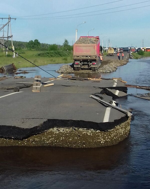 Самосвал насыпает щебень на разрушенном участке дороги в подтопленном городе Тулуне Иркутской области
