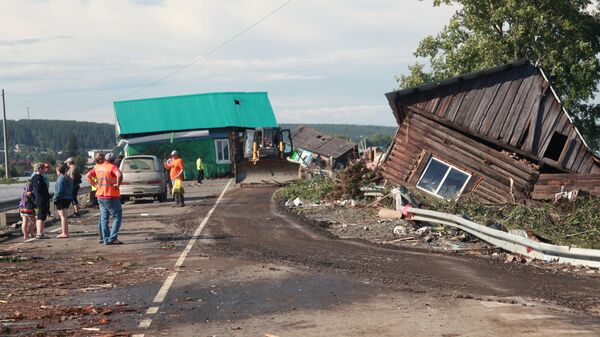 Люди и работники спасательных служб около разрушенных в результате наводнения домов в городе Тулун в Иркутской области