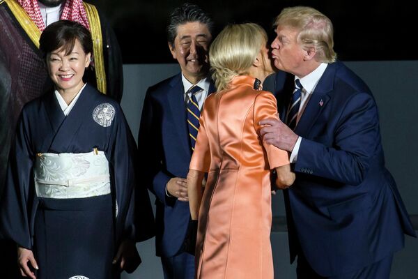 Президент США Дональд Трамп целует супругу Эммануила Макрона Бриджит на саммите G-20 в Осаке