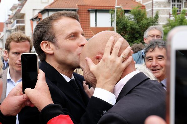 Президент Франции Эммануэль Макрон целует голову своего сторонника после голосования на европейских выборах в Ле-Туке