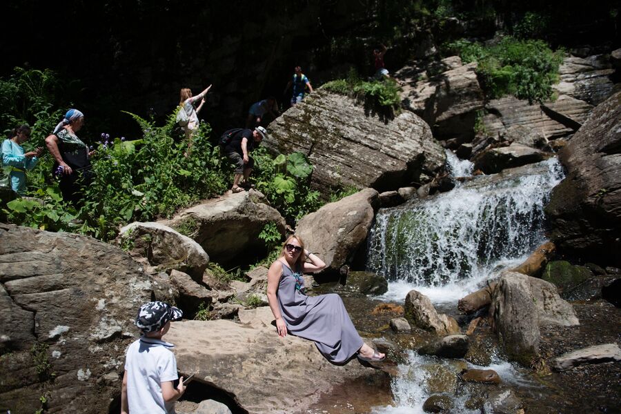 Туристы в природном парке водопадов Менделиха на горнолыжном курорте Роза Хутор в Сочи