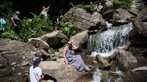 Туристы в природном парке водопадов Менделиха на горнолыжном курорте Роза Хутор в Сочи