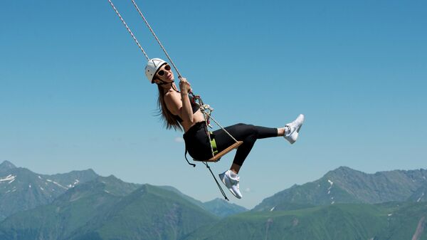 Девушка катается на тарзанке на горнолыжном курорте Роза Хутор в Сочи