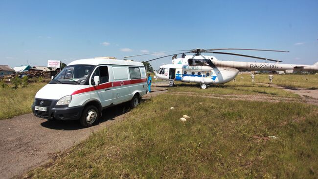 Вертолет Ми-8АМТ с медицинским модулем на борту и машина скорой помощи в Тулунском районе Иркутской области, где происходит ликвидация последствий паводка