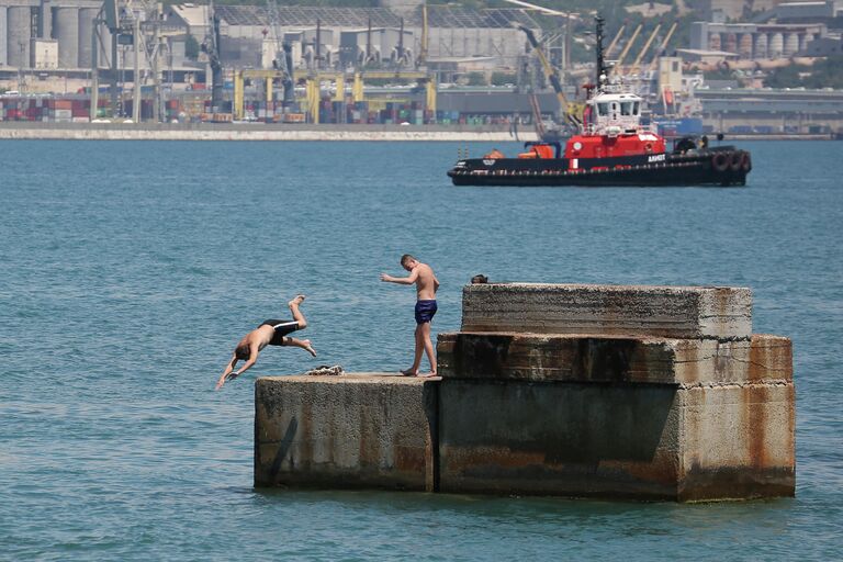 Молодые люди прыгают в море с пирса Новороссийска