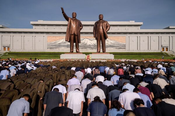 Люди кланяются статуям Ким Ир Сена и Ким Чен Ира в 25-ю годовщину смерти Ким Ир Сена в Пхеньяне