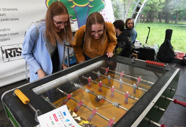 Девушки стоят у настольной игры в хоккей на фестивале науки и технологий Geek Picnic 2019 Жить вечно/Immortality