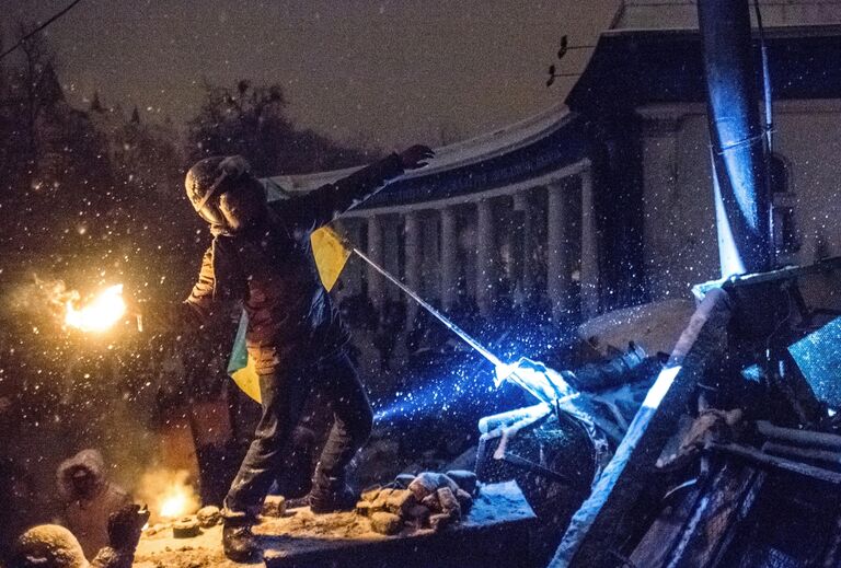 Участник акции протеста кидает бутылку с зажигательно смесью в полицейских на улице Грушевского в Киеве