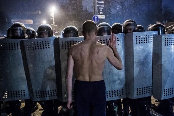 Участник акции протеста разговаривает с сотрудниками спецподразделения милиции Беркут на улице Грушевского в Киеве