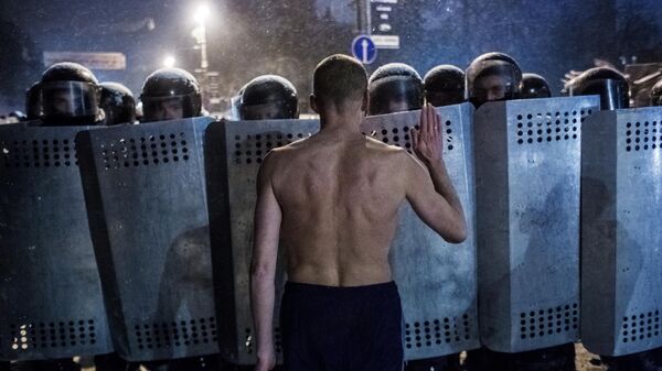 Участник акции протеста разговаривает с сотрудниками спецподразделения милиции Беркут на улице Грушевского в Киеве