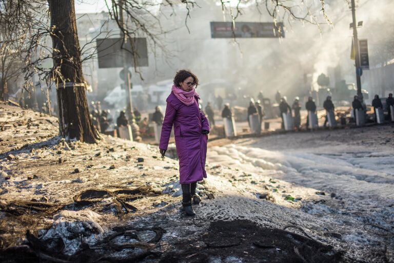 Жительница Киева пытается перейти через нейтральную территорию между баррикадами оппозиции и кордоном милиции