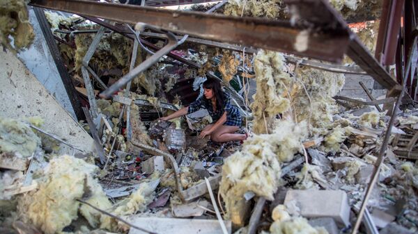 Девушка разбирает завалы в продуктовом магазине, который был разрушен прямым попаданием мины