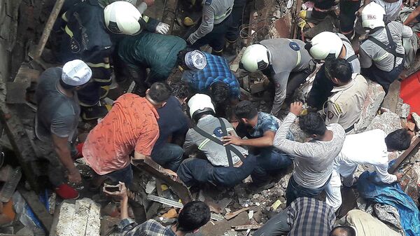 Спасатели и жители ищут выживших на месте рухнувшего здания в Мумбаи, Индия. 16 июля 2019 