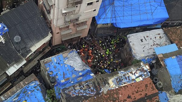 Спасатели и жители ищут выживших на месте рухнувшего здания в Мумбаи, Индия. 16 июля 2019