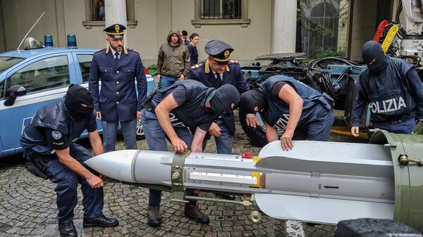 Итальянские полицейские переносят ракету класса воздух-воздух после обнаружения тайника с оружием и боеприпасами в Турине