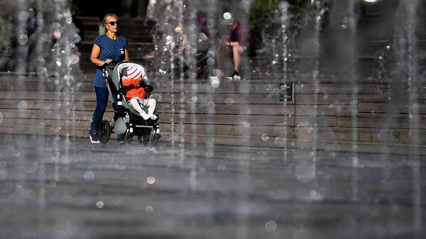 Женщина гуляет с коляской в парке искусств Музеон