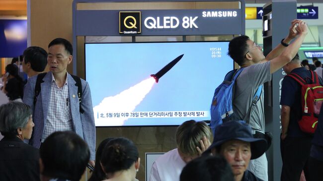 Жители Сеула смотрят по телевизору выпуск новостей о запуске ракет с территории КНДР