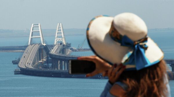 Девушка фотографирует Крымский мост через Керченский пролив