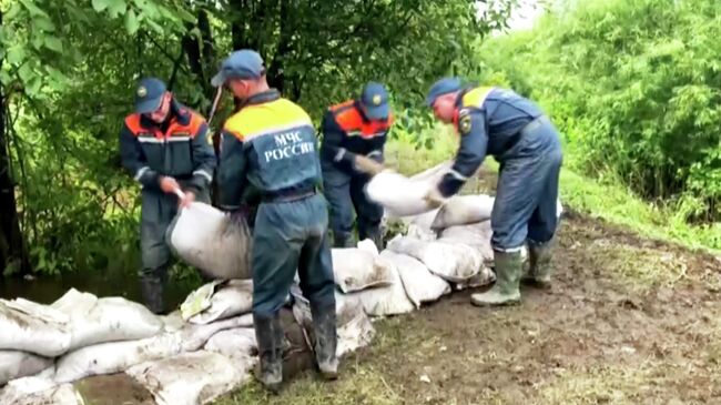 Сотрудники МЧС РФ укладывают мешки с песком в подтопленном районе Амурской области.