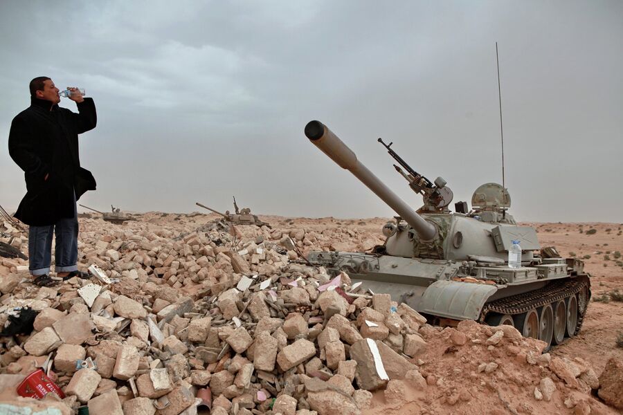 Мужчина у танков ливийской армии, захваченных силами оппозиции, в пустыне под городом Адждабия