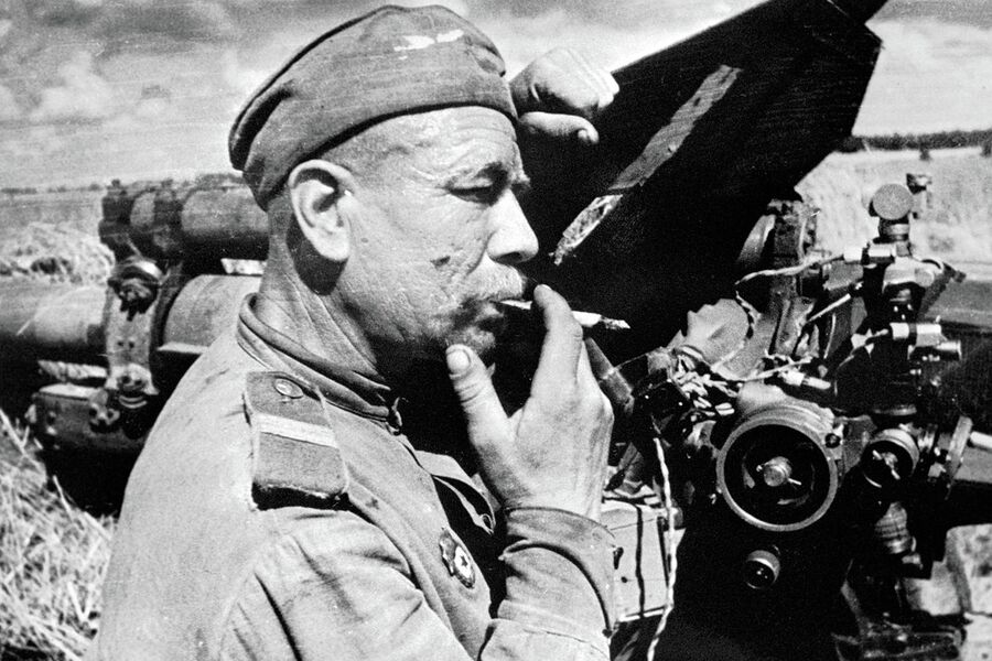 Советский артиллерист-гвардеец отдыхает у своей 122-мм гаубицы М-30 после боя с немецкими танками под Каунасом. 3-й Белорусский фронт