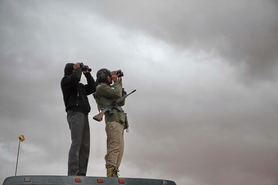 Наблюдатели с биноклями высматривают в небе города Рас-эль-Ануфа истребители войск Муамара Каддафи