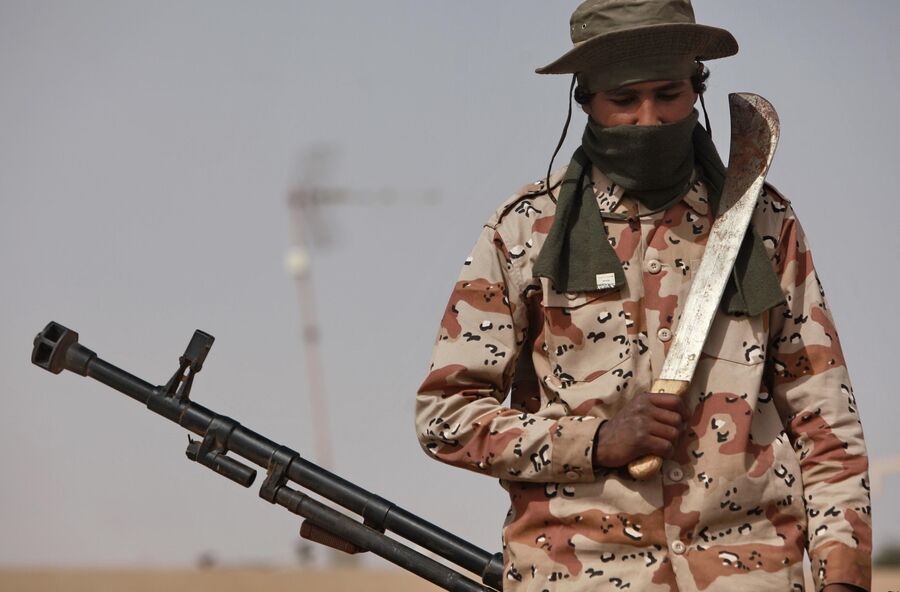 Боец с тесаком возле зенитной пушки в захваченном повстанцами городе Рас-эль-Ануфе на востоке страны