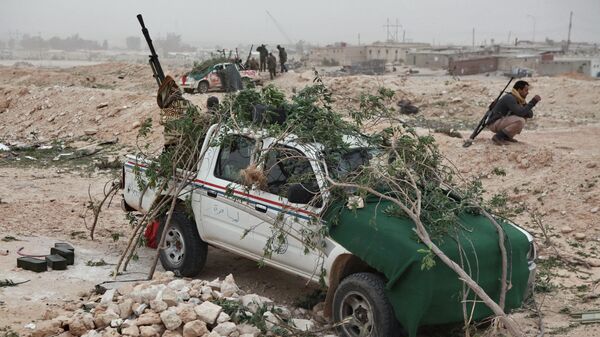 Боец сил ливийской оппозиции у автомобиля с зенитным пулеметом, замаскированный ветками от атак с воздуха, у города Брега